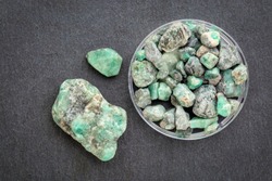 raw emerald gemstones (mineral beryl) with inclusions mined in Brazil on a gray slate stone