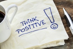 think positive - motivational slogan on a napkin with a cup of coffee