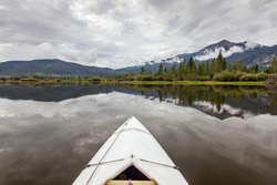 bow of a white kayak on Lake Dillon in Colorado Rocky Mountains, cloudy sky with water reflections