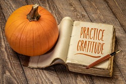 practice gratitude inspirational note - handwriting in a retro journal with a pumpkin against rustic wood, Thanksgiving theme