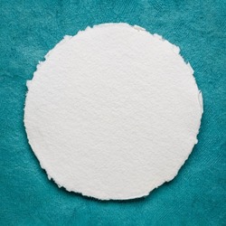 circular sheet of blank white watercolor paper against turquoise handmade bark paper