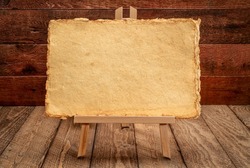 small easel sign with handmade yellow paper against rustic and weathered wood background