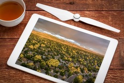late summer sunrise over residential area of Fort Collins and foothills of Rocky Mountains in northern Colorado, reviewing an aerial image on a digital tablet