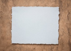 gray and brown abstract - a sheet of blank Indian handmade rag paper against textured bark paper, copy space