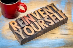 reinvent yourself - motivational words in vintage letterpress wood type against grunge, painted wood with a cup of coffee