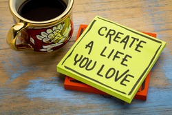 Create a life you love advice or reminder - handwriting in black ink on a sticky note with a cup of coffee