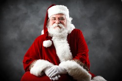 Santa Claus looking into the camera with traditional background and hands crossed in front of him