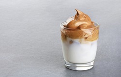 Glass with dalgona coffee on a gray background. Ice milk and foamy whipped coffee. Copy space.