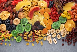 Dried fruits and berries on gray background top view. Lemons, oranges, bananas, raisins, cranberries, kiwi, cherries, ginger, plums, strawberries, dried apricots, tangerines, dates, pineapples, figs,