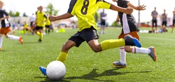 Young african soccer player running fast and kicking white football ball. Youth footballers compete in tournament match. Soccer athlete kicking ball. School sports competition