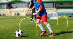 Child playing soccer ball on practice unit. School physical education class for kids. Football sports training camp. Exercise class for sporty boys
