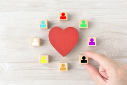 Heart object surrounded by wooden blocks with colorful human pictogram