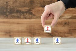 Human's hand picking up wooden block with female pictogram