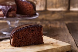 Slice of homemade chocolate cake on wooden cutting board, rustic style
