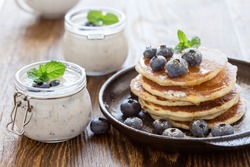 Healthy organic blueberry smoothie in glass jar and buttermilk pancakes with fresh berries on rustic wooden table