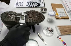 Police scientist investigates with a scale on a shoe sole tape tread involved in crime lab murder, concept image