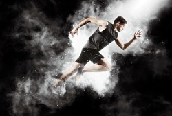 Sporty young man running on black smoke background