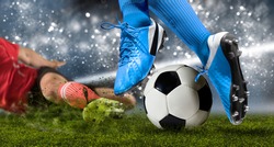 Football player man in action on dark arena background. Soccer player making sliding tackle
