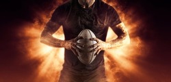 Rugby player holds ball on fire background. Sports banner. Horizontal copy space background