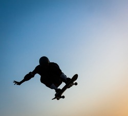 skateboarder jumping with blue sky in background