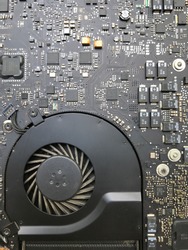 Close up on the printed circuit main motherboard of a laptop computer showing intricate parts of micro processor and air vent fan for heatsink cooling system for the cpu
