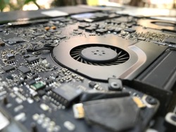Close up on the printed circuit main motherboard of a laptop computer showing intricate parts of micro processor and air vent fan for heatsink cooling system for the cpu