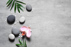 Spa concept on stone background, palm leaves, flower and zen, grey stones, top view, copy space