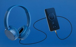 Headphones and mobile phone on blue