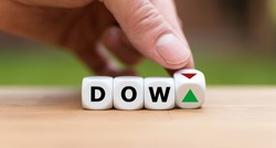 Hand is turning a dice and changes the direction of an arrow symbolizing that the Dow Jones Index is changing the trend and goes up instead of down (or vice versa)