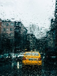 a yellow taxi is photographed through a window with raindrops. The taxi moves through the streets of istanbul on a rainy day