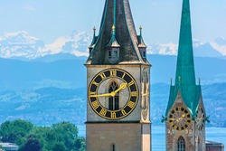 Saint Peter and Fraumünster Church in Zurich (Switzerland) in front of lake Zurich and the Swiss Alps