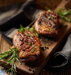 Roasted duck breast with the addition of aromatic herbs on a wooden board, close-up