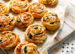 French Puff Pastry Pinwheels stuffed with salmon, cheese and spinach on on baking paper, close up view 