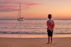 Boy watching the sunset from the beach