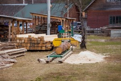 Sawmill. Process of machining logs in equipment sawmill. Machine saw saws the tree trunk on the plank boards. Wood sawdust work sawing timber wood. Selective focus