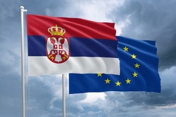 Serbia and EU flag together next to each other on a flagpole. Serbian flag in front of a European Union flag on a stormy sky background