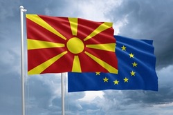 North Macedonia and EU flag together next to each other on a flagpole. North Macedonian flag in front of a European Union flag on a dramatic stormy sky background