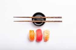 Set of different sushi with salmon, tuna and shrimp, soy sauce and chopsticks over white background, top view. Traditional Japanese sushi concept, close-up, flat lay
