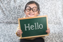 Little asian girl holding a chalkboard with a word HELLO. Concept of Hello day, Greetings, Introduction and lifestyle