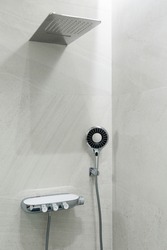 Marble gray wall, rain shower and shower head. Modern bathroom design. Vertically framed shot.