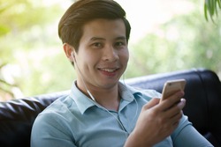 Young Asian man listen music on smart phone in cafe