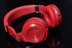 wireless headphones in red, on a dark background with reflection