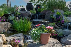 Waterscape fountain urns create a beautiful tranquil backyard oasis surrounded by bright pink and red flowers and ornamental grasses