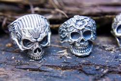 Silver rings skulls closeup in full face on a dark wooden surface. Jewelry in biker and rocker style