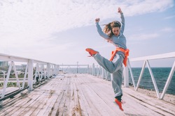 Hip hop dancer in fashion sportswear jumping and dancing in the street. Outdoor workout in cold weather.