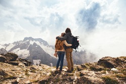 Man and woman standing and hugging on the top of the mountain, autumn hike with backpacks, alpine view