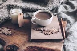 Cup of coffee and candle on rustic wooden serving tray with blanket. Spending autumn weekend in the cozy bed.