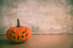 Halloween spooky ghost and mummy pumpkin on wooden floor with grey loft concrete wall background, vintage toned color photo with old and haunts concept