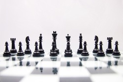 black chess pieces on a glossy chessboard on a white background