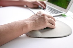 Man's fingers clicking on mouse, resting his wrist on wrist rest.  Close up shot.